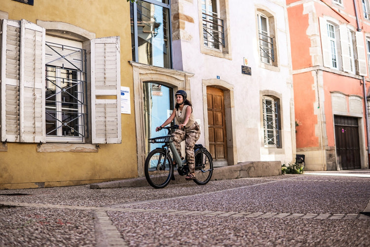 Rider on a Moustache Mardi electric bike along a colourful town street