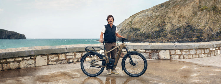 Rider standing with a Riese & Müller Delite electric bike beside a coastal bay