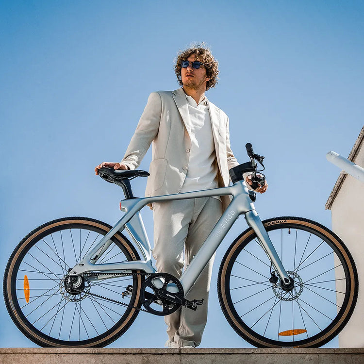 Rider standing with a pale silver Fiido Air lightweight electric bike