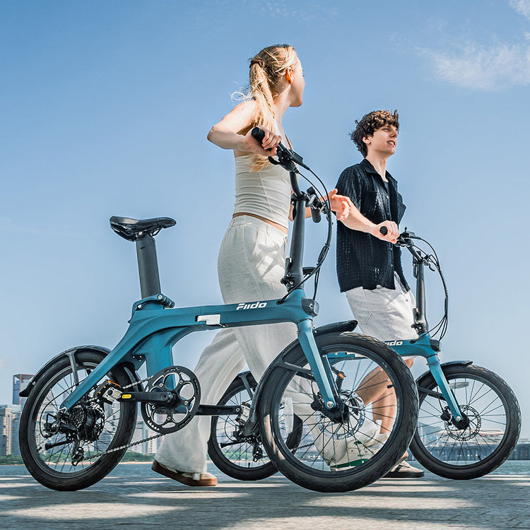 Two riders with blue Fiido X folding electric bikes in the city